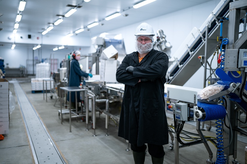 A person in a white helmet and a black coat standing in a factoryAI-generated content may be incorrect.